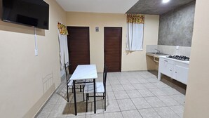 Cocina compacta con comedor, televisor montado en la pared y estufa a gas.