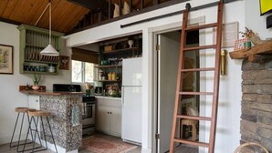 Una cocina con una isla central, una escalera y una pared de piedra rústica.