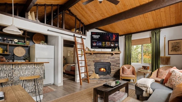 Una sala de estar acogedora con chimenea, un televisor montado encima y un comedor con barra.