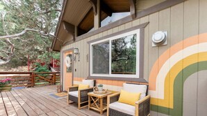 Una terraza de madera con mobiliario de mimbre y un ventanal grande.