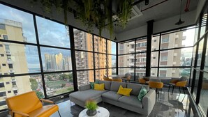 A modern lounge with a glass floor, a grey sofa with yellow cushions, and a round table with a plant. - Cozy studio in Panama City (Panamá)