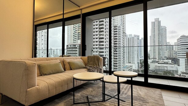 A modern living room with a sofa, two round tables, and a large window offering a city view. - Cozy studio in Panama City (Panamá)