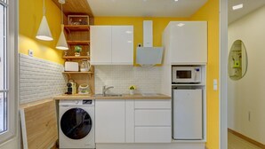 A compact kitchen with white cabinets, a washing machine, a microwave, and a sink.