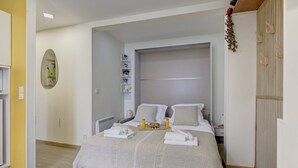 A hotel room with a bed, a bedside table, a mirror, and a wardrobe.