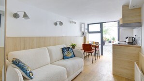 A modern living room with a sofa, a dining area, and a kitchen. - TheBlueStay 72 - Cozy Studio - Marais District (Paris)