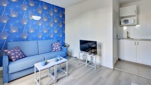 Una sala de estar moderna con un sofá azul, una mesa de centro y un televisor de pantalla plana.