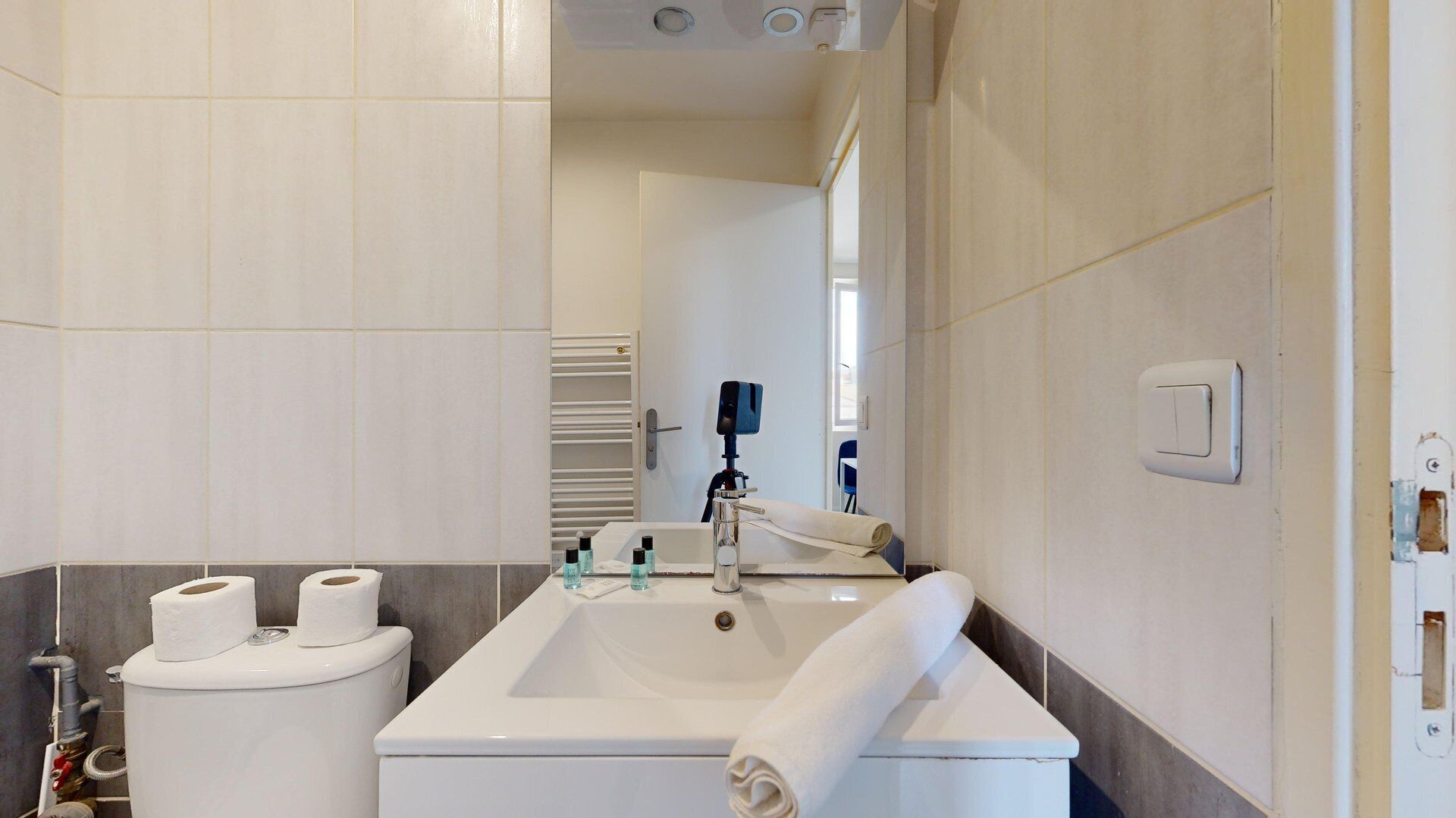 Un baño moderno con lavamanos, inodoro y toalla blancos.