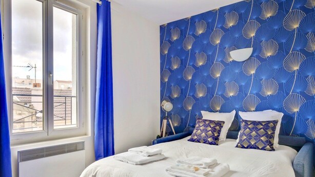 Una habitación de hotel con una cama grande, cortinas azules y un papel tapiz estampado.