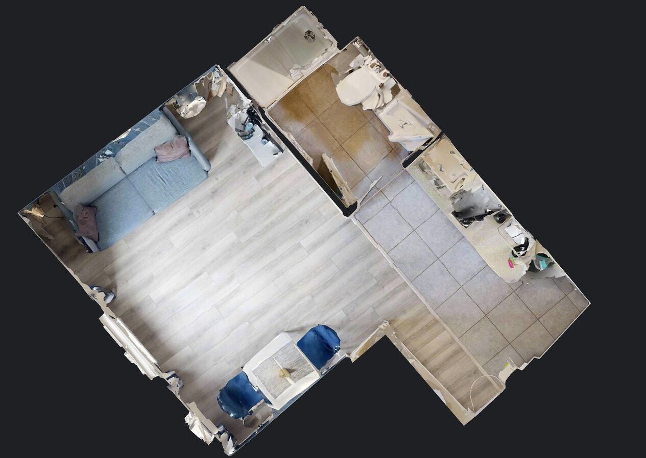 Vista cenital de una habitación de hotel con una cama grande, un escritorio pequeño, una silla, un armario y un baño con inodoro y lavabo.
