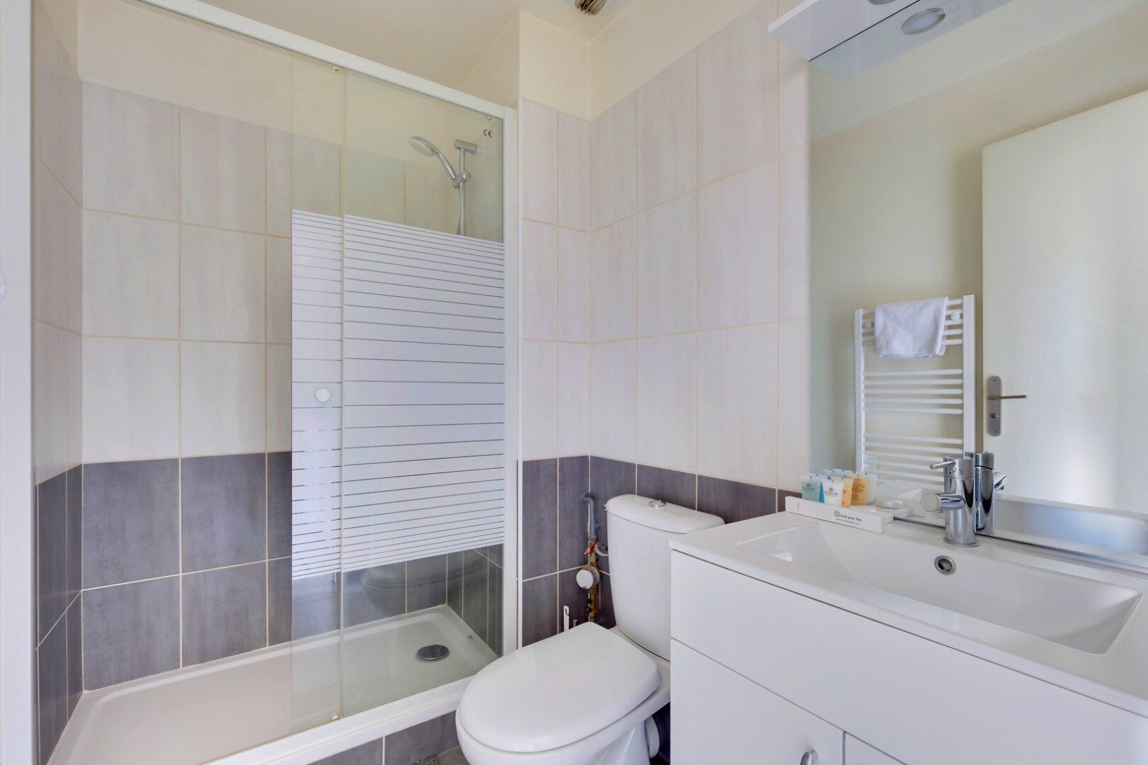 Een moderne badkamer met een douchecabine van glas, een wit toilet en een wastafel met spiegel.