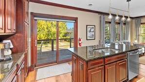 A kitchen with a large island, sliding glass doors, and a view of a deck. - Lake View Condo - Walk to Saugatuck (Douglas)