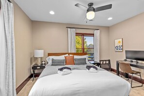 A hotel room with a bed, a desk, a chair, a television, and a ceiling fan. - Lake View Condo - Walk to Saugatuck (Douglas)