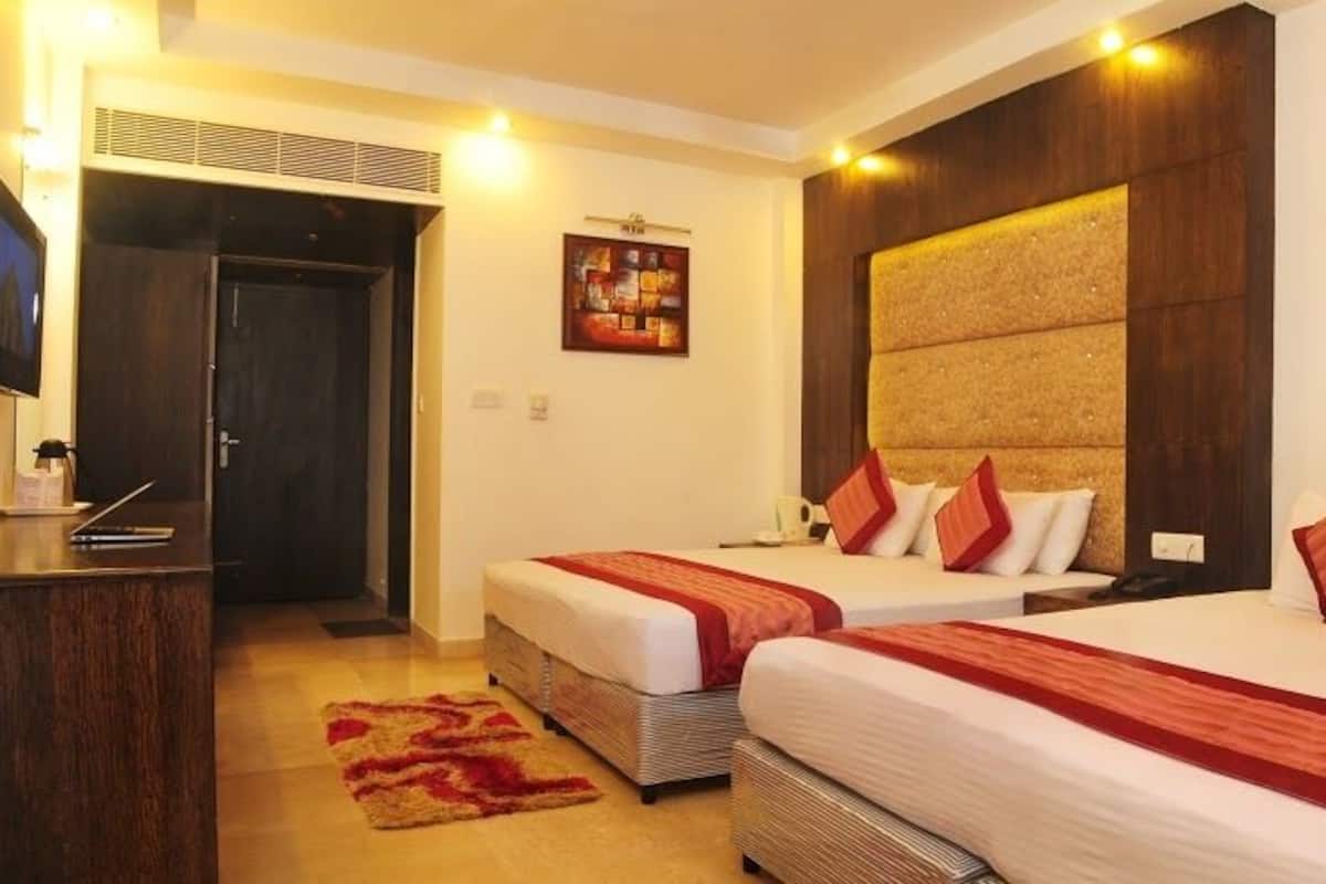 A hotel room with two beds, a desk, and a television.