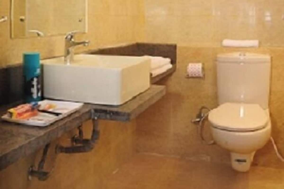 A bathroom with a sink, mirror, toilet, and a towel rack.