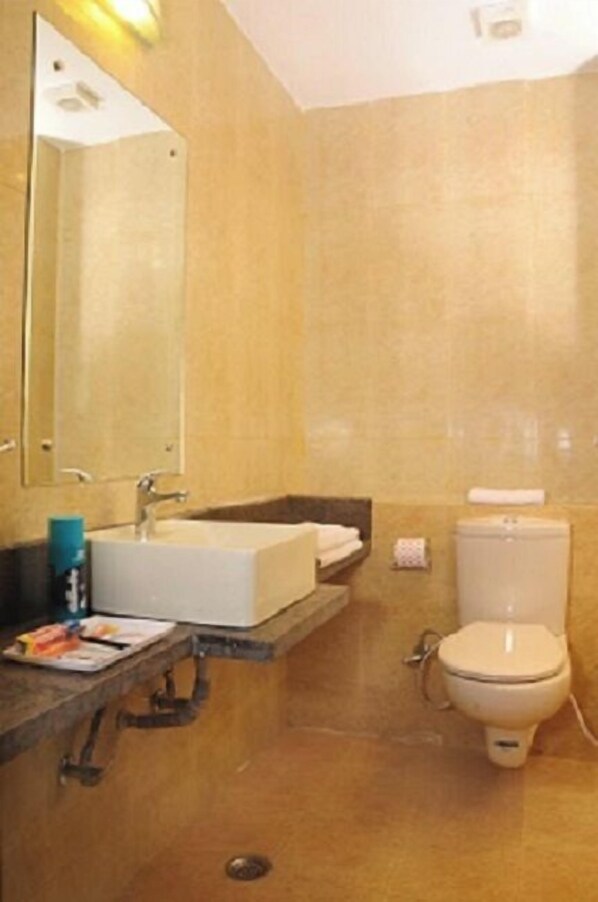 Un baño con lavabo, espejo, inodoro y toallero.