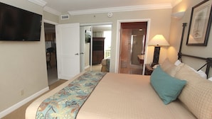 A hotel room with a bed, a TV mounted on the wall, and a door leading to a bathroom.