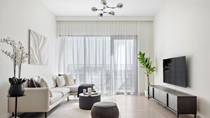 Un salon moderne avec un canapé, un pouf et un téléviseur à écran plat fixé au mur.