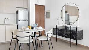 Une cuisine moderne avec un coin repas, comprenant une table ronde, des chaises blanches, une console en marbre noir et un grand miroir.