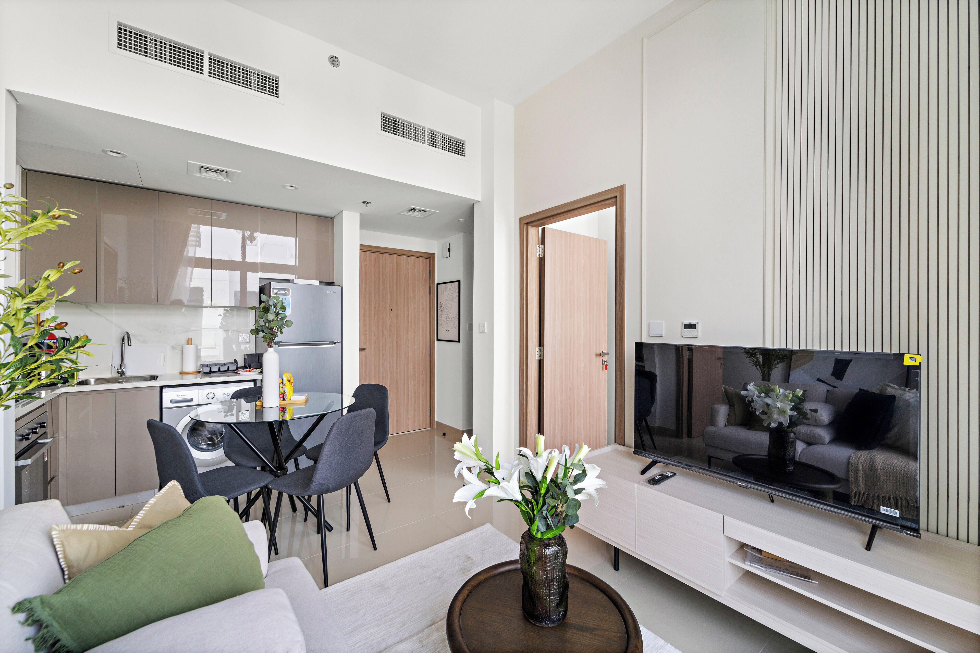 En moderne stue med et fladskærms-tv, en sofa, et sofabord og et spiseområde med stole og et bord.