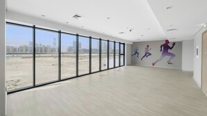 A spacious room with large windows, a city view, and a wall mural of runners.