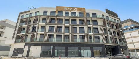 A multi-story building with a sign reading "AZIZI GARDENS".