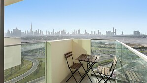 Un balcon avec une table et des chaises, offrant une vue sur les toits de la ville et une autoroute.