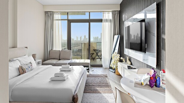 Une chambre d’hôtel moderne dotée d’un grand lit, d’un canapé, d’une télévision et d’un balcon offrant une vue sur la ville.