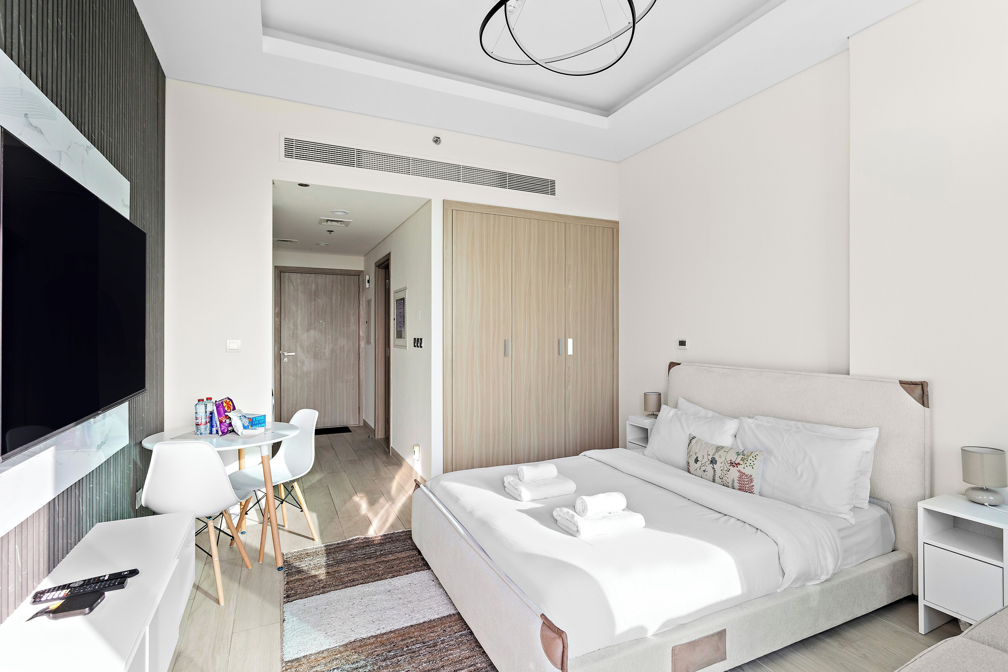 Een moderne hotelkamer met een groot bed, een televisie, een bureau met stoelen en een kledingkast.