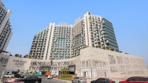 Un immeuble moderne de grande hauteur, doté de nombreux balcons et d’une entrée imposante.