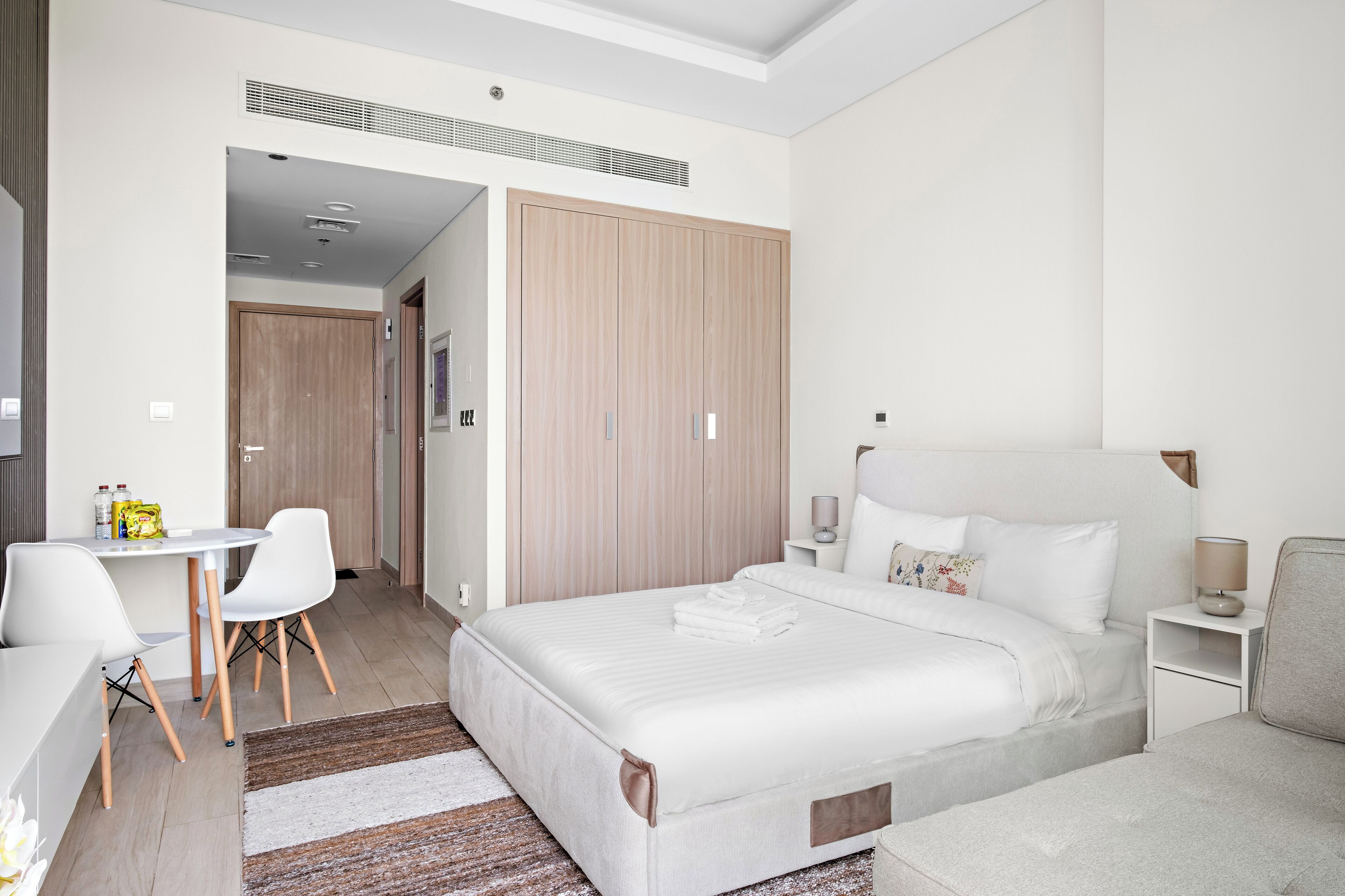 A modern bedroom with a large bed, a desk, and a wardrobe.