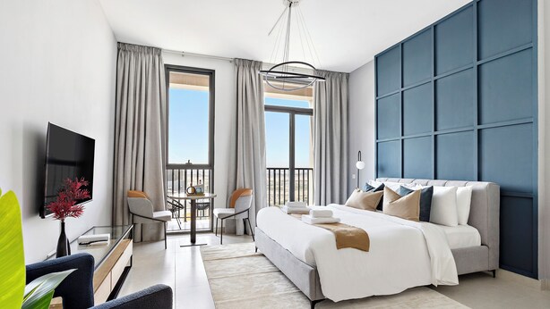 Een moderne hotelkamer met een groot bed, een televisie, een balkon en een eethoek.