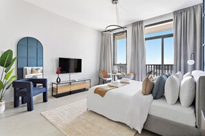 Een moderne hotelkamer met een groot bed, een televisie, een bureau en een balkon met uitzicht.