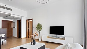 Una sala de estar moderna con un televisor de pantalla plana, un sofá blanco, una mesa de centro y una planta en maceta.