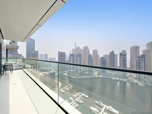 Ein hoher Balkon mit Blick auf die Stadt, Glasgeländern und einem Hafen mit Booten.