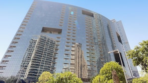 Un immeuble de grande hauteur doté d’une façade moderne en verre, de nombreux balcons et d’un angle incurvé.