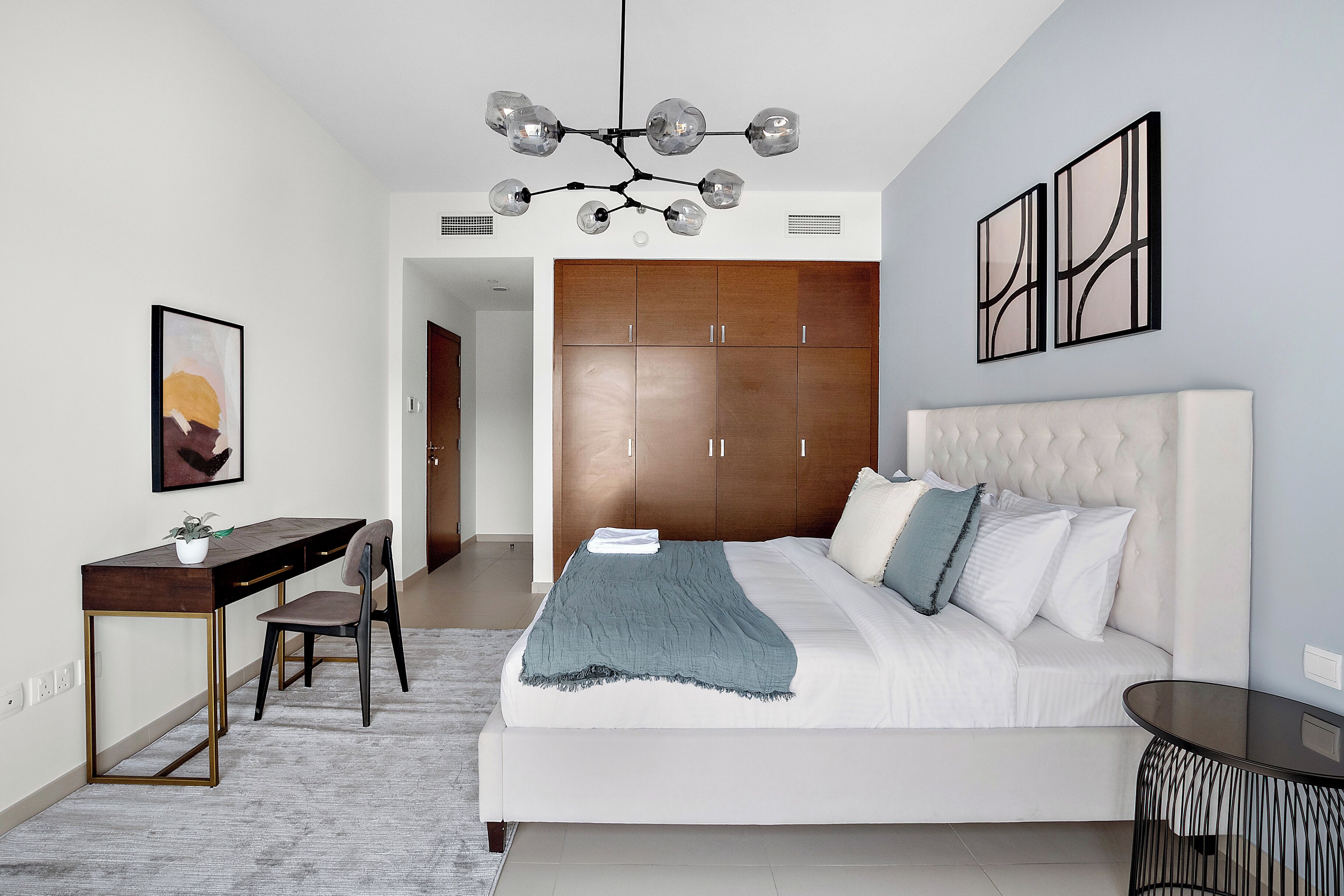 Un dormitorio moderno con una cama grande, un escritorio y un armario.