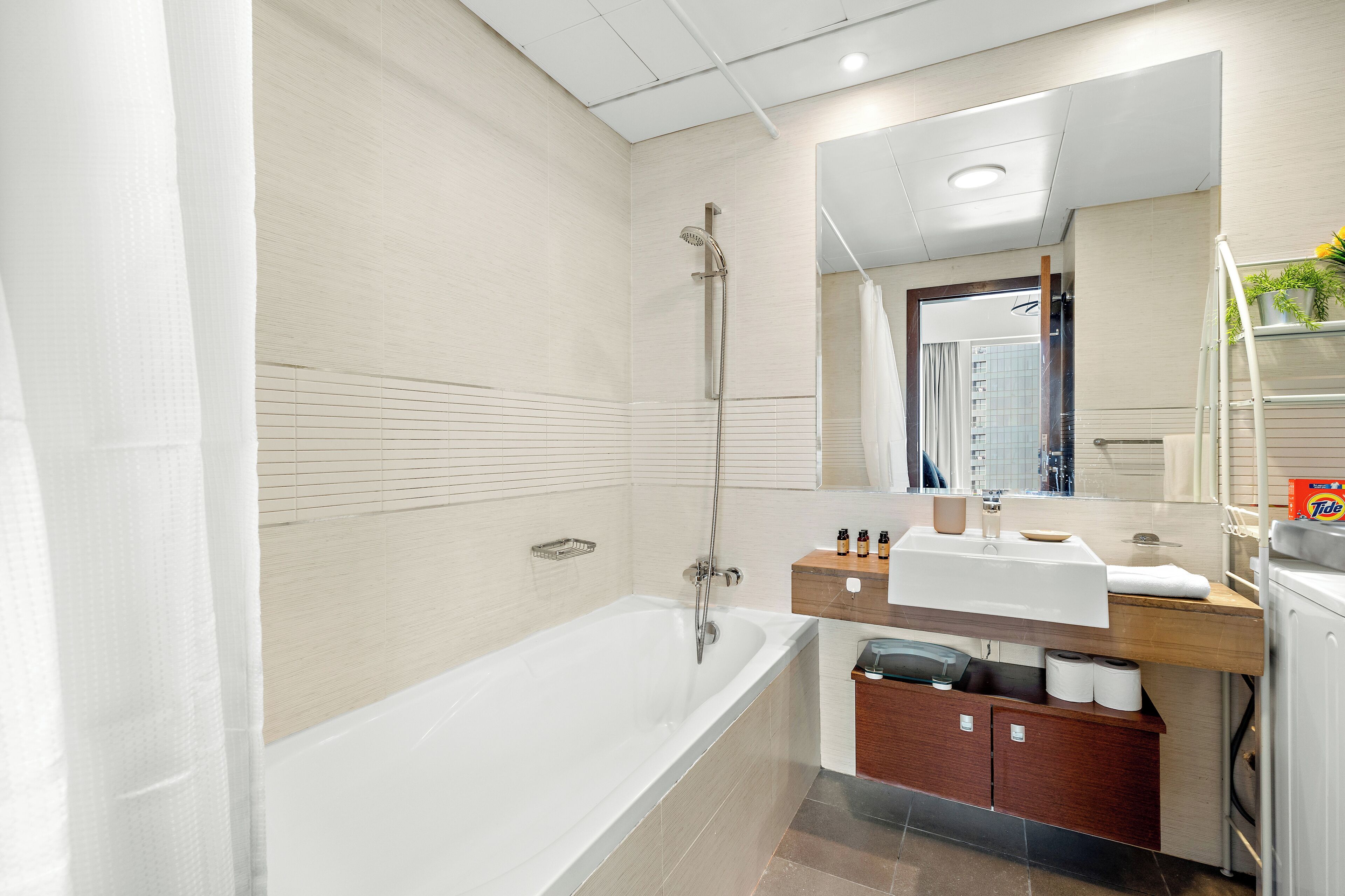 A modern bathroom with a bathtub, a shower, a vanity with a mirror, and a toilet.