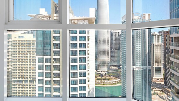 Une vue à travers la fenêtre d’un immeuble moderne, doté de plusieurs étages, de grandes fenêtres et surplombant un ciel dégagé.