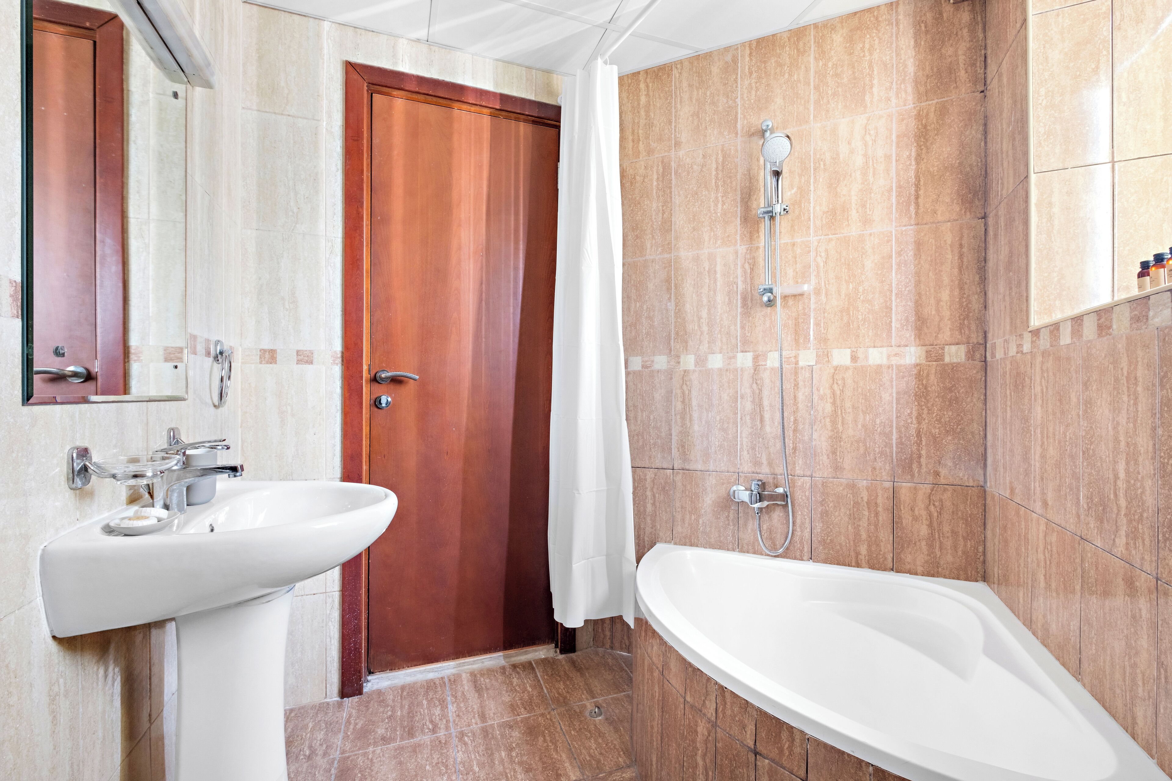 A bathroom with a sink, a shower, and a door.