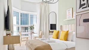 Une chambre d’hôtel moderne, dotée d’un grand lit, d’un bureau, d’une chaise, d’une télévision et d’une fenêtre avec des rideaux.