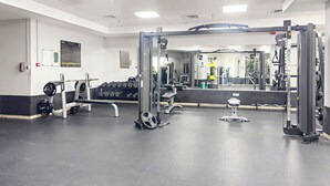 Une salle de sport équipée de matériel de musculation, d’haltères et d’un miroir.
