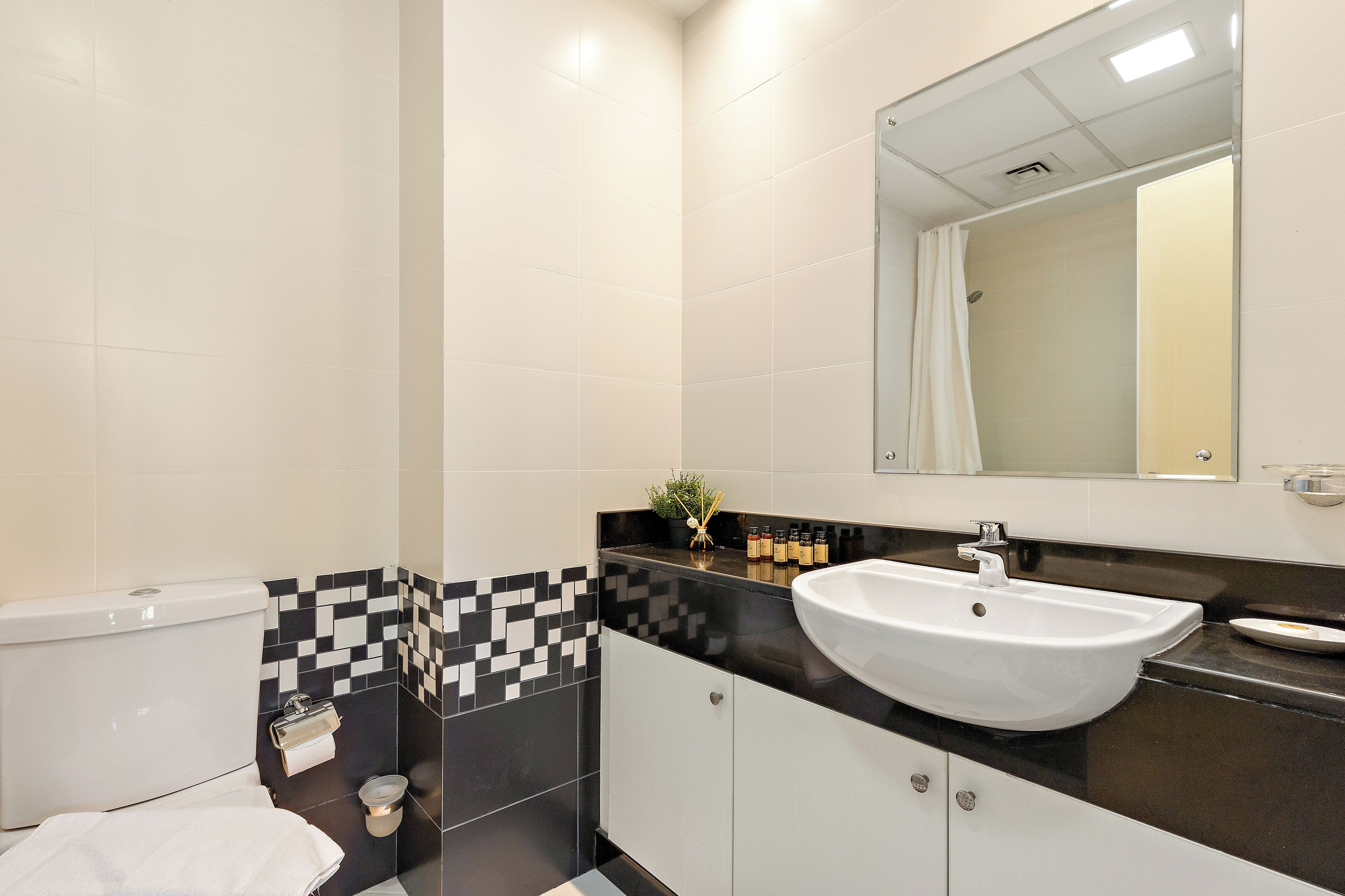 Ein modernes Badezimmer mit einem weißen Waschbecken, Wandfliesen in Schwarz und Weiß und einer Toilette.
