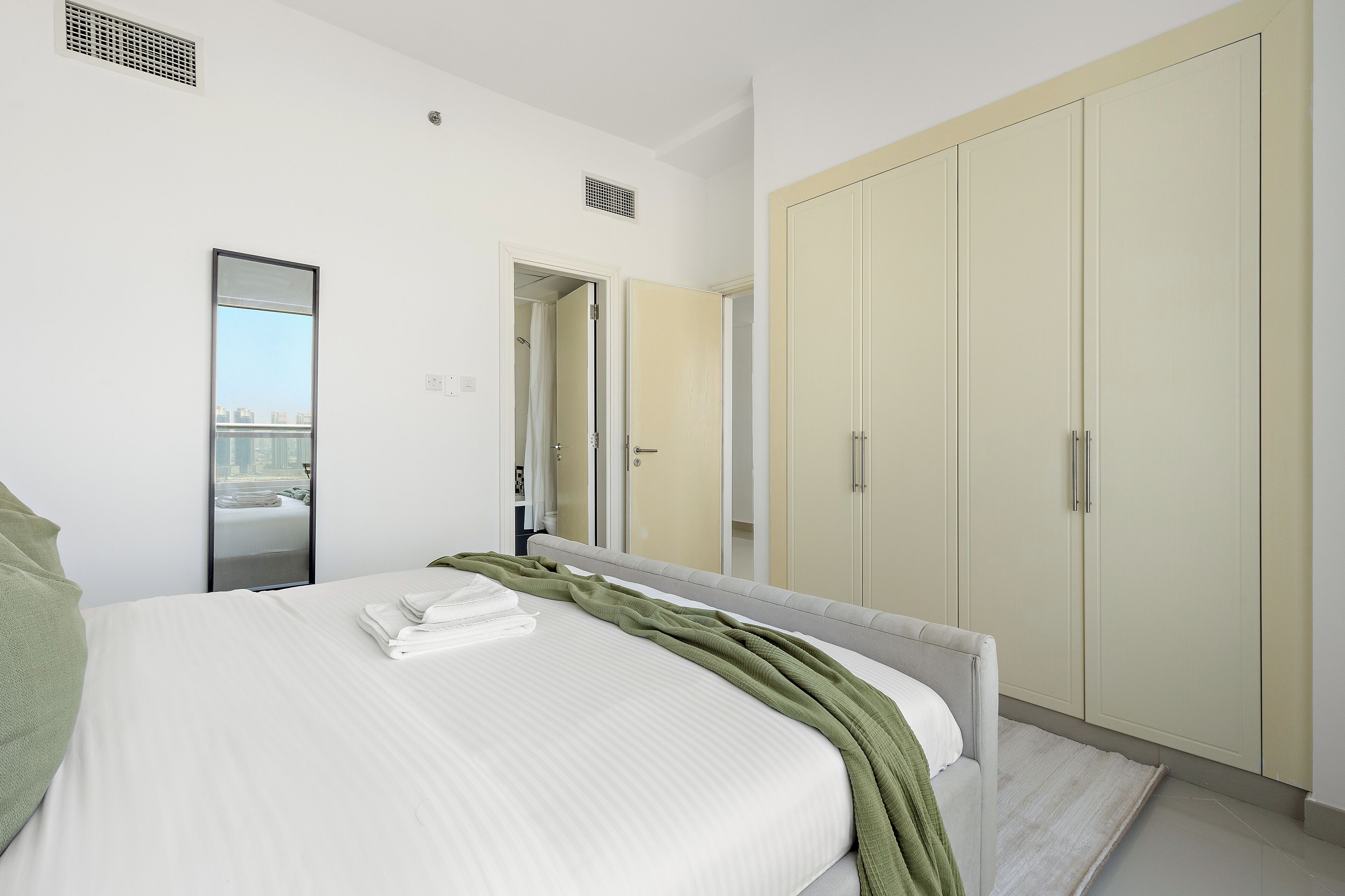 Une chambre d’hôtel avec un grand lit, une armoire, un miroir et une vue sur la ville.