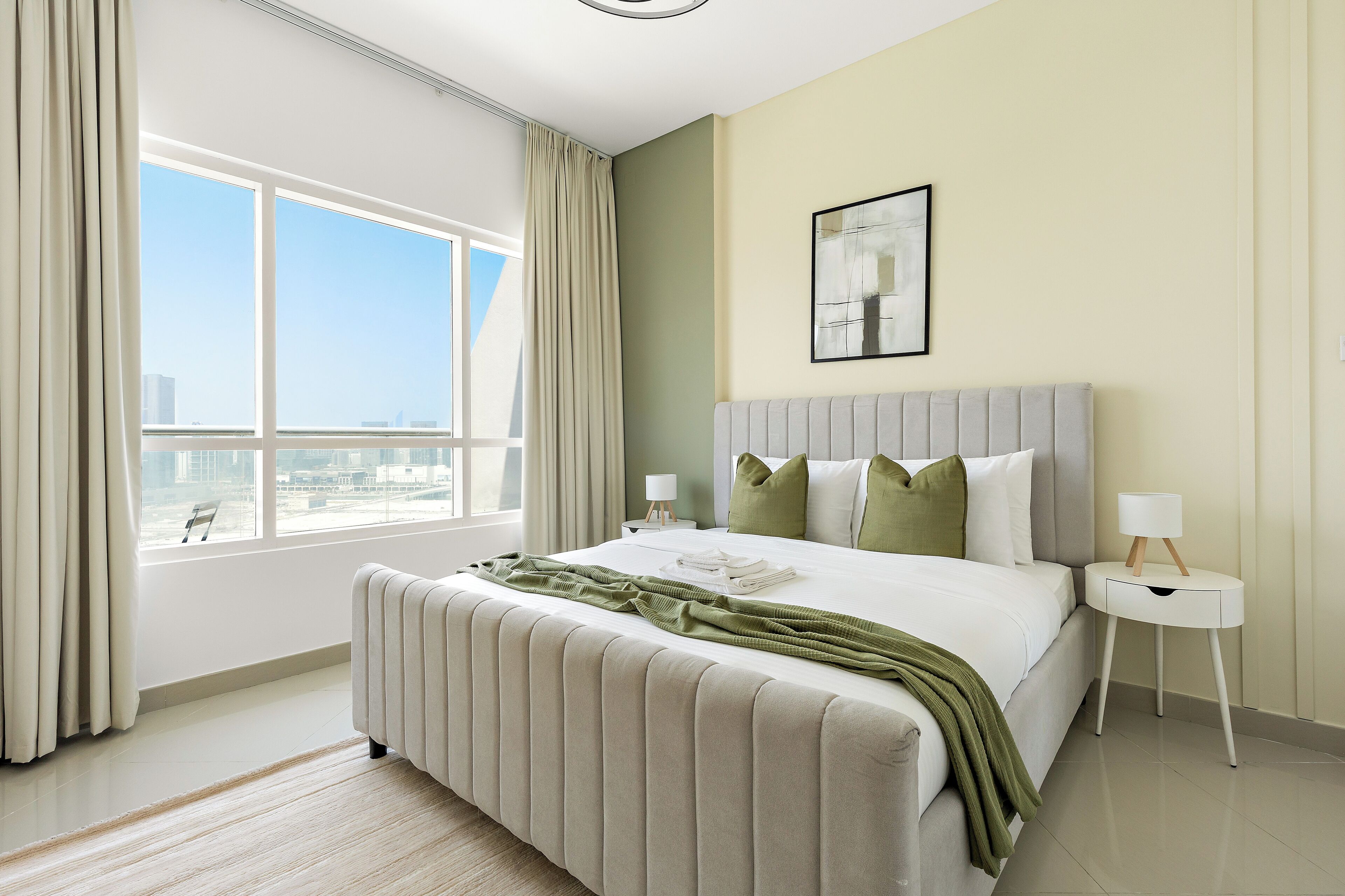 Una moderna camera d'hotel con un grande letto, vista sulla città e una finestra con tende.