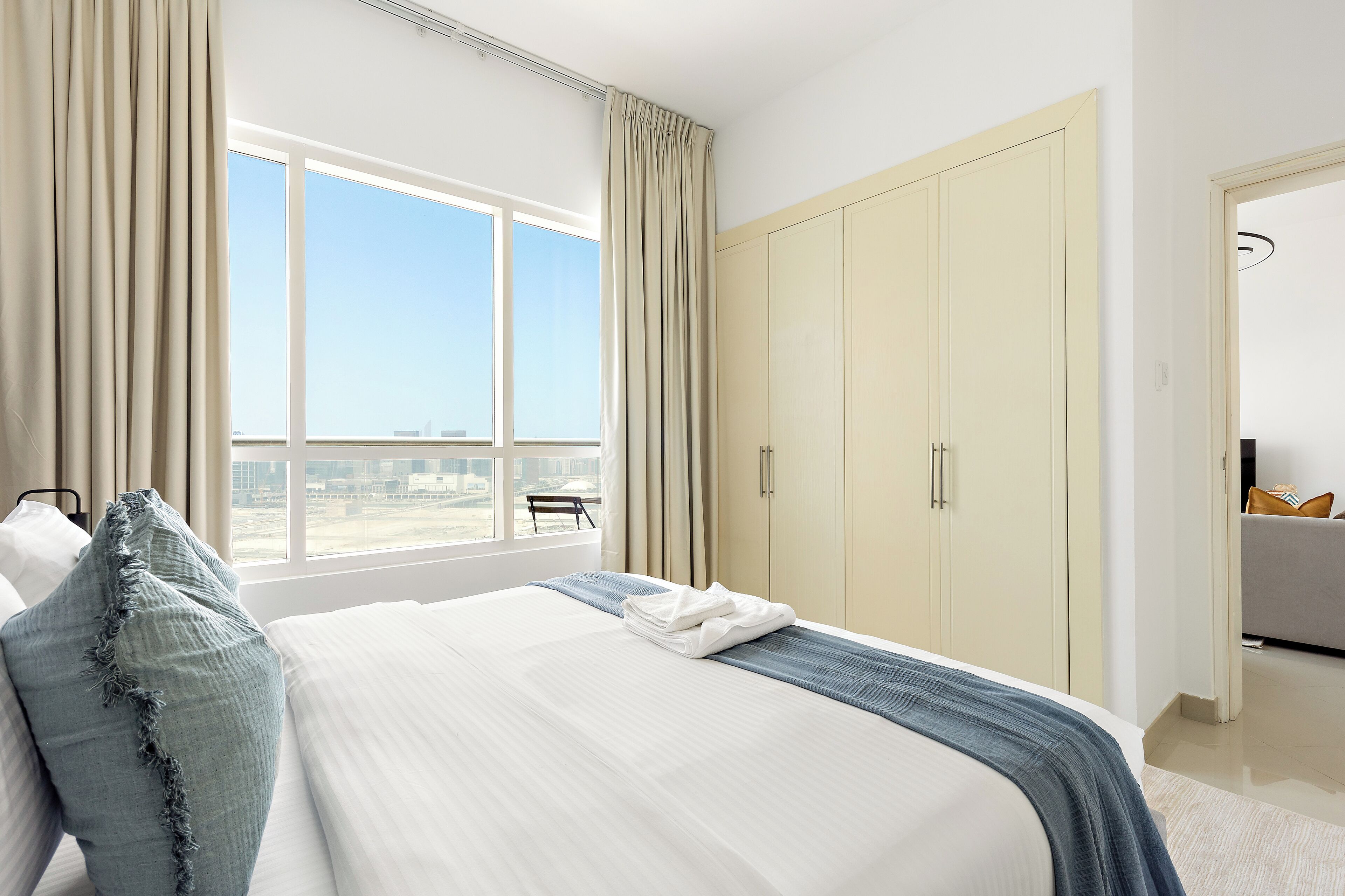 Une chambre d’hôtel avec un grand lit, une armoire et une vue sur la ville par la fenêtre.