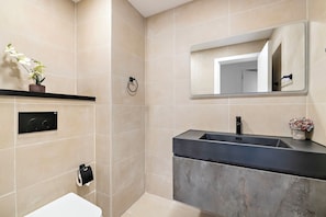 A modern bathroom with a toilet, sink, and mirror.