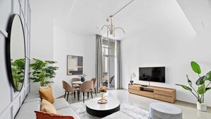 Een moderne woonkamer met een bank, voetenbankje, salontafel en televisie.