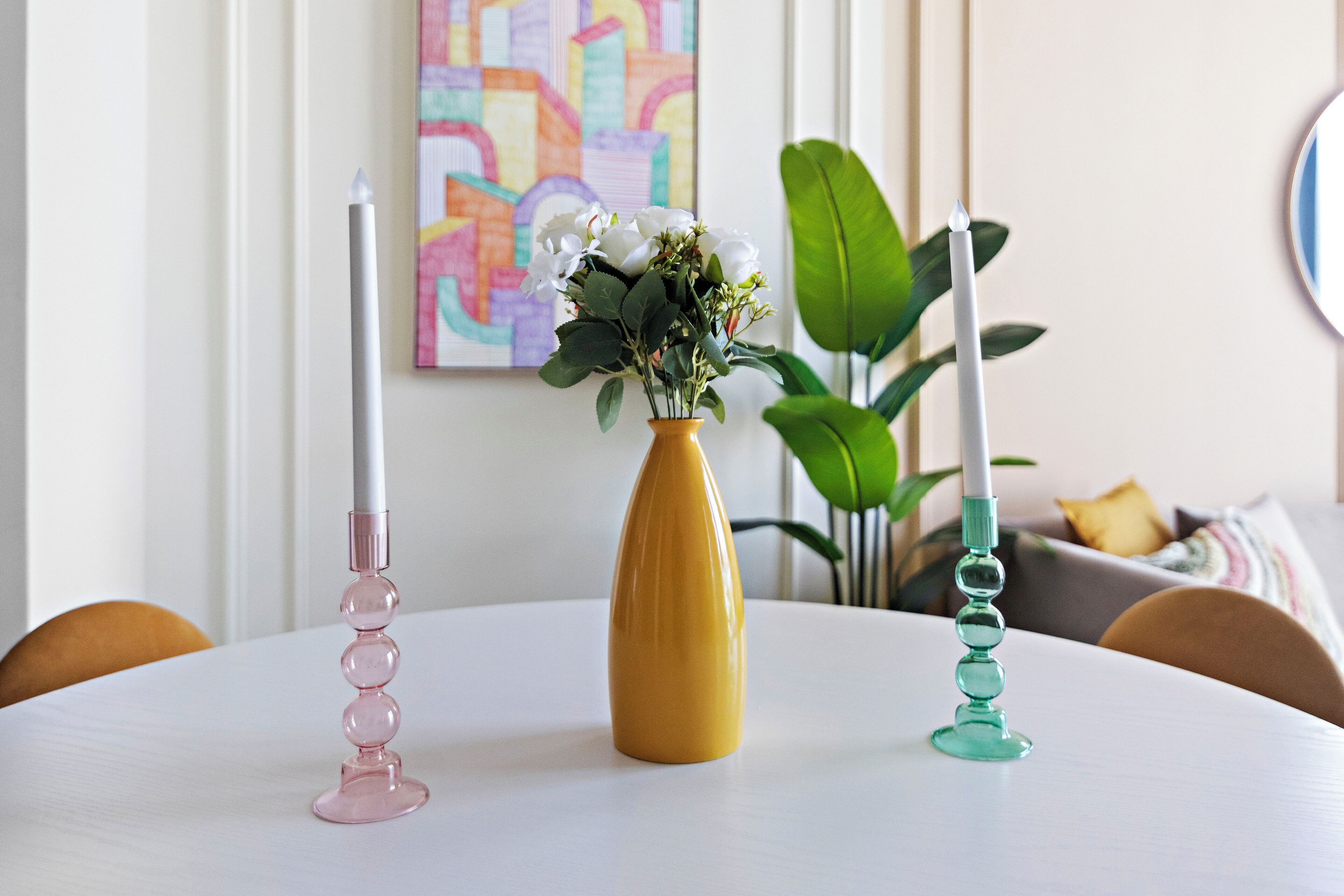 Una mesa redonda con tres velas de distintos diseños.