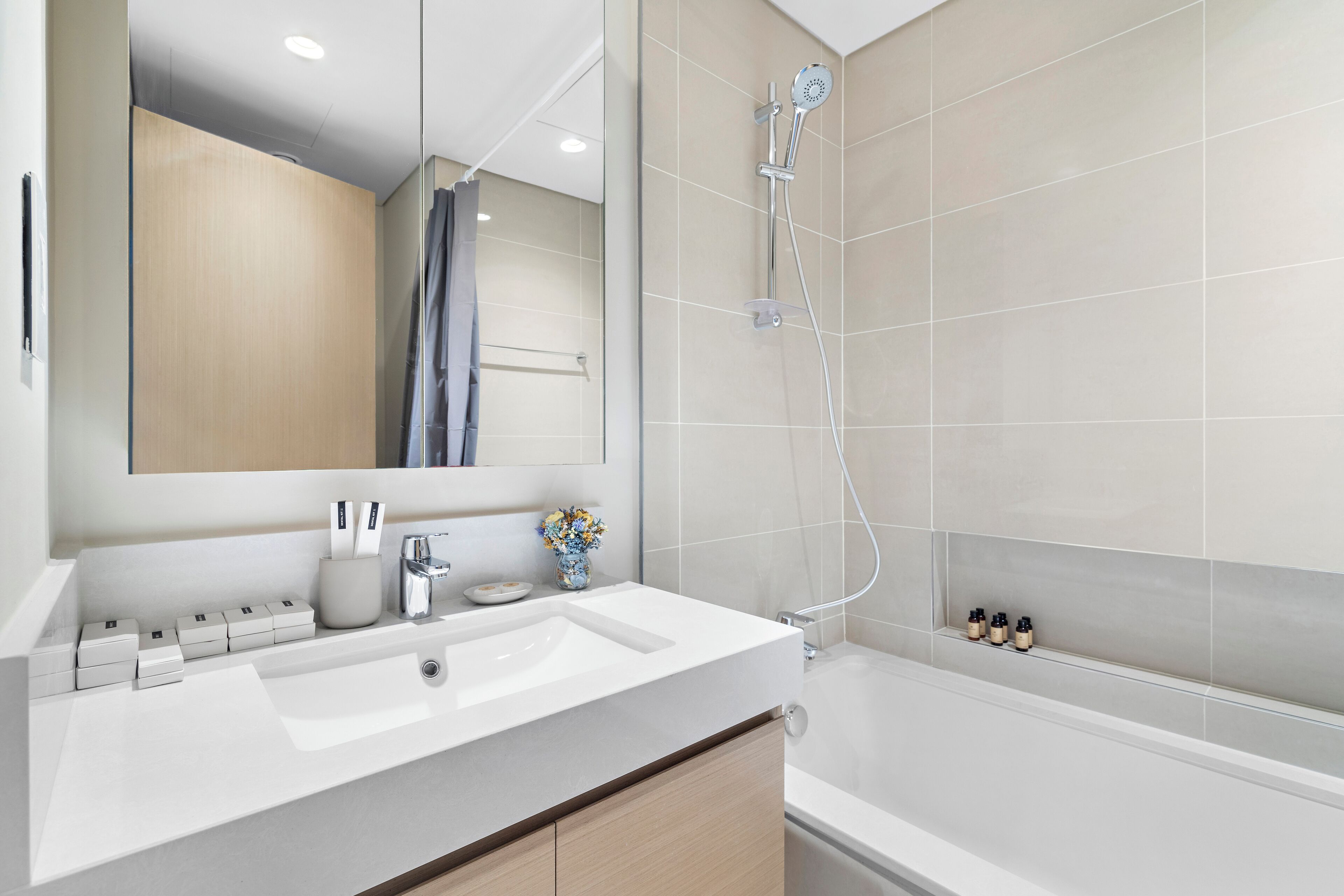 Un bagno moderno con lavandino, specchio e doccia bianchi.