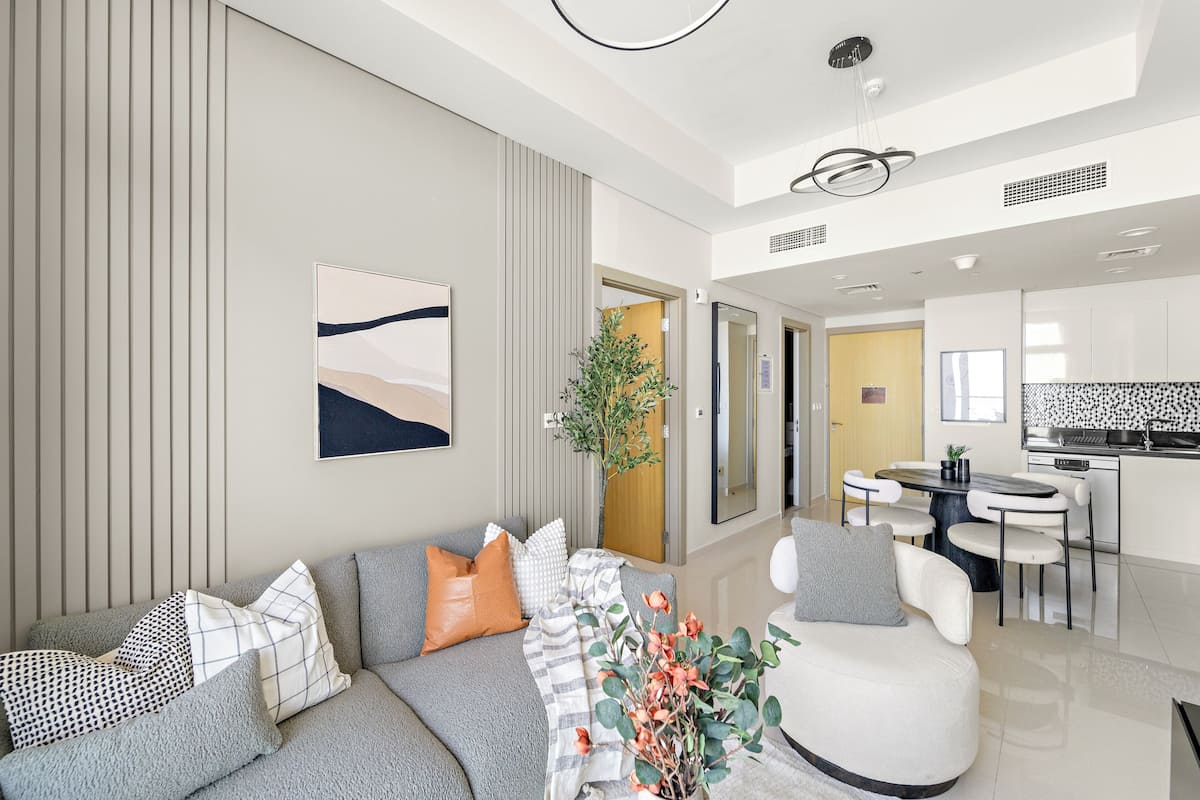 A modern living room with a sofa, a dining table, and a kitchen area.